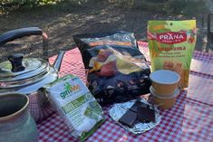 a picnic table with food and drinks on it, including coffee bag, tea pot, kettle