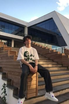 a young man sitting on top of wooden steps in front of a building with stairs