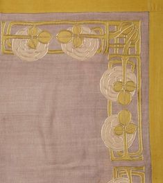 a yellow and grey table cloth with an embroidered design on it, in the shape of a rectangle