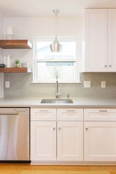 a clean kitchen with white cabinets and stainless steel dishwasher on the counter top