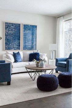 a living room with blue and white furniture in the corner, along with two large paintings on the wall