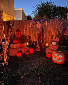 halloween decorations in the yard with pumpkins and hay bales on the ground next to a fence