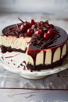 a cheesecake with cherries and chocolate toppings on a white cake platter