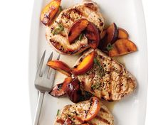 grilled chicken and peaches on a white plate with a silver serving fork next to it