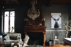 a living room filled with furniture and a chandelier hanging from the ceiling over a fire place