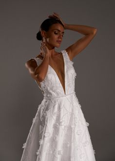 a woman in a white dress posing for the camera with her hand on her head