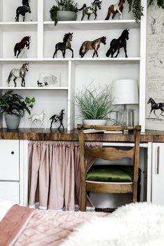 a desk with shelves filled with toy horses on top of it and plants in vases