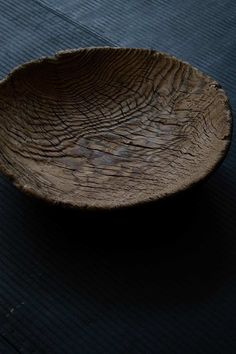 a wooden bowl sitting on top of a black mat covered in woodgrain material