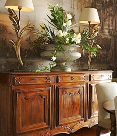 two lamps are sitting on top of a wooden cabinet in front of a floral arrangement