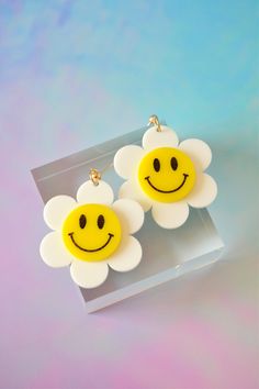 "These happy daisies will be sure to put a smile on your face! Made of lightweight acrylic, they're cut in the shape of a groovy daisy with a classic smiley in the middle and finished with a brass ball post stud for closure. Materials: acrylic, brass hardware Measurements: 2.5\" drop length, 2.1\" wide Most earrings are made to order; please allow up to 5 days handling time." Playful White Flower Earrings, Fun White Flower-shaped Jewelry, Playful White Earrings For Spring, Smile Earrings, Smiley Face Earrings, Groovy Daisy, Smiley Happy, Happy Daisy, Funny Earrings