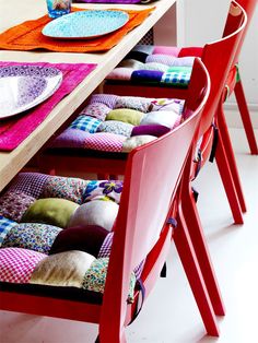 a red chair sitting next to a wooden table filled with plates and placemats