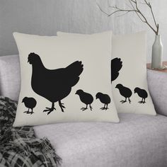 two black and white pillows with chicken silhouettes on them, sitting on a couch