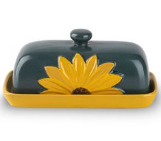 a yellow and green dish with a flower on the bottom, sitting in front of a white background