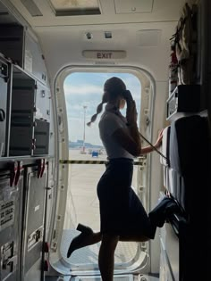 a woman is standing in the doorway of an airplane