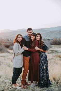 four people standing together in an open field