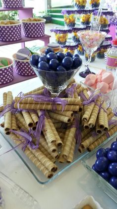 there are many desserts on the table with purple and blue candies in them