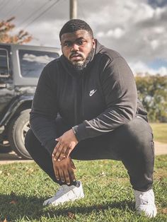 a man squatting in the grass with his foot on the ground next to him