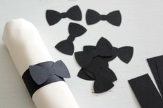 black bow ties are laid out on top of a roll of toilet paper next to some pieces of felt