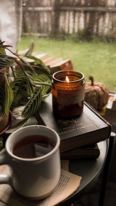 a cup of coffee sitting on top of a table next to a book and candle