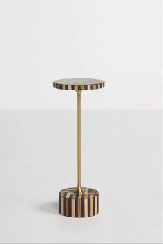 a black and white striped table with a gold metal stand on it's side