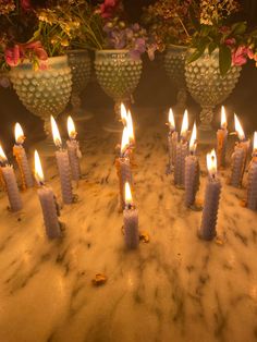 many candles are lit in front of some vases