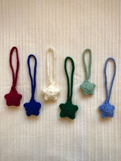 four crocheted bow ties are lined up on a white surface, one is green and the other is blue