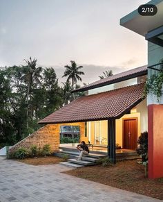 a person sitting on the steps in front of a house with a red and white roof