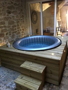 a hot tub sitting on top of a wooden deck next to a stone wall and steps