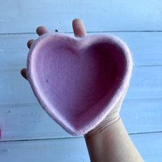 someone holding up a heart shaped object in their hand