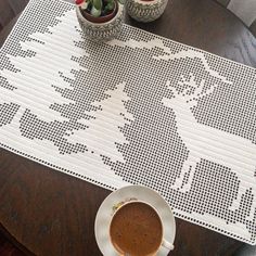 a cup of coffee sitting on top of a table next to a potted plant