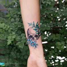 a woman's arm with a skull and flowers tattoo on it