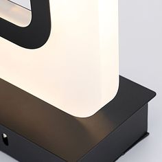 a black and white lamp is on top of a wooden stand with a square light