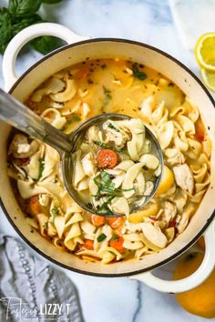 a ladle full of chicken noodle soup with lemons and parsley on the side