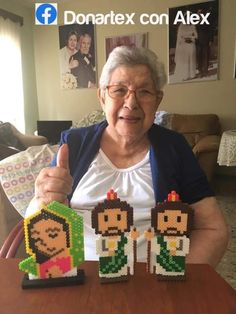 an old woman holding up some legos on top of a table with other items