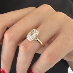 a woman's hand wearing a gold ring with an oval shaped diamond on it