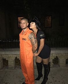 a man in an orange prison outfit standing next to a woman with tattoos on her arm