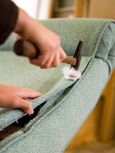 someone using a pair of scissors to clean the back of a green chair with fabric