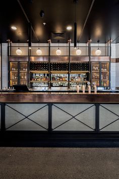 an empty bar with lots of bottles on the shelves and lights hanging from the ceiling