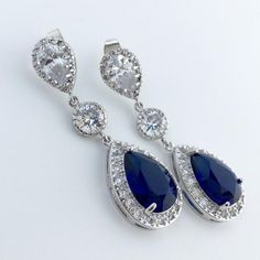 a pair of blue and white earrings with diamonds on them, set against a white background