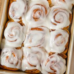 a pan filled with cinnamon rolls covered in icing