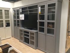 a large entertainment center with glass doors and shelves on each side, in a showroom