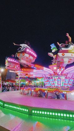 people ride on the merry go round at an amusement park with lights and rides lit up