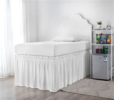 a white bed in a bedroom next to a book shelf filled with children's books