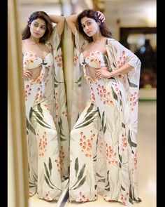 two beautiful women standing next to each other in front of a mirror wearing matching outfits