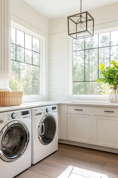 a washer and dryer in a white laundry room with wood flooring, windows, and cabinets