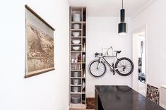 a bike mounted to the side of a wall next to a wooden table and shelf