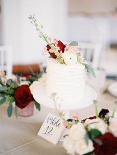 a white wedding cake with flowers and greenery on the top is sitting on a table