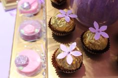 some chocolates with pink frosting and flowers on them are sitting on a table