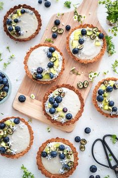 blueberry and pistachio tarts on a cutting board surrounded by other food items