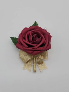 a red rose with green leaves and gold ribbon on it's head is shown against a white background